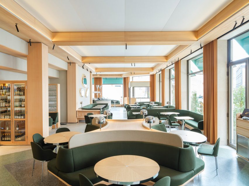 Restaurant interior with larch wood column, beams and table and green upholstered seating
