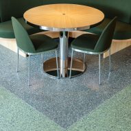 Restautant interior with green upholstered seating, wood tables and terrazzo flooring