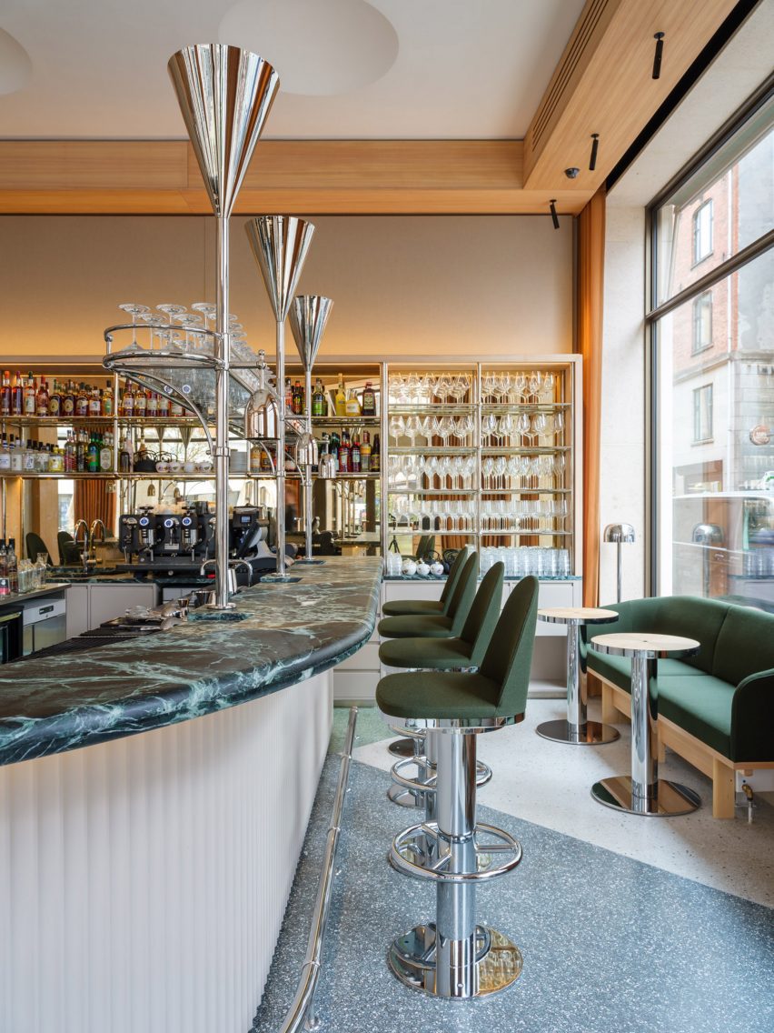 Restaurant bar with a green marble countertop, green bar stools and terrazzo flooring
