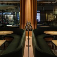 Restautant interior with green upholstered seating and wood tables