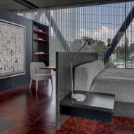 A bedroom with a grey bed and dark marble partition walls and furniture
