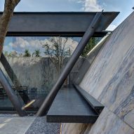 Sloping marble exterior walls with bench seating and a home with a black steel structure