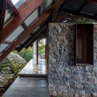 A home with stone walls and metal pitched roof with a wood structure