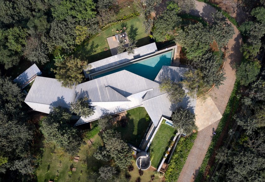 Birds-eye view of a home in India with a swimming pool and angular metal roof