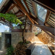 An outdoor space with sandy stone steps and a pitched metal roof with timber structure overhead