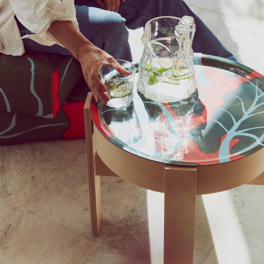 Circular wooden table with a red tabletop with a leaf print