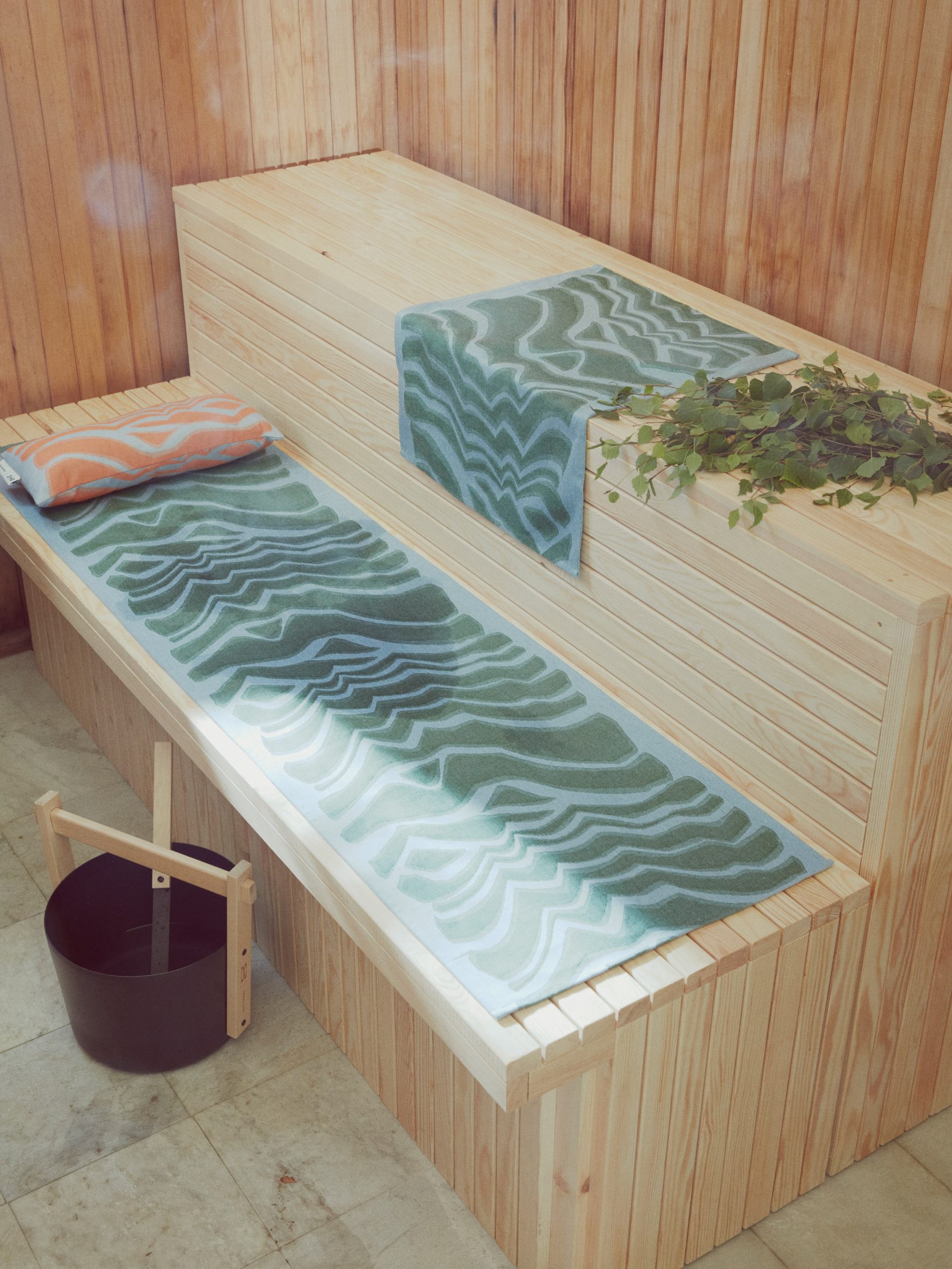 Wooden sauna seat with blue and green patterned towels