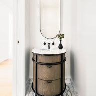 Interior of a small bathroom with a circular wood vanity and decorative floor tiling