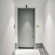 Apartment entrance hall with decorative floor boarder tiles, white walls and a grey door