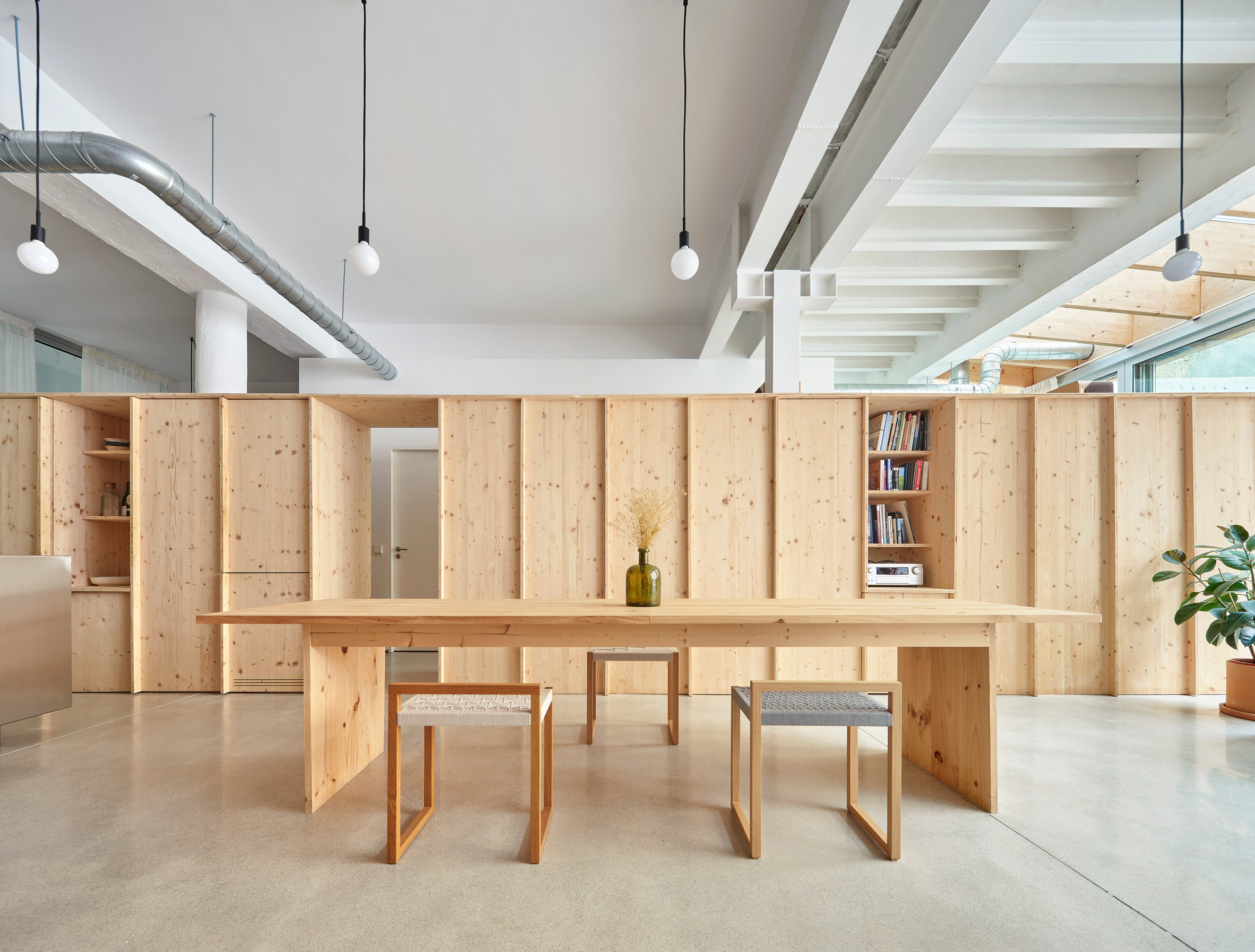 Open-plan living space with wooden room divider by Auba Studio