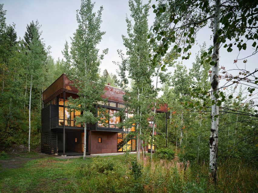 Rectilinear oxidized steel house surrounded by trees