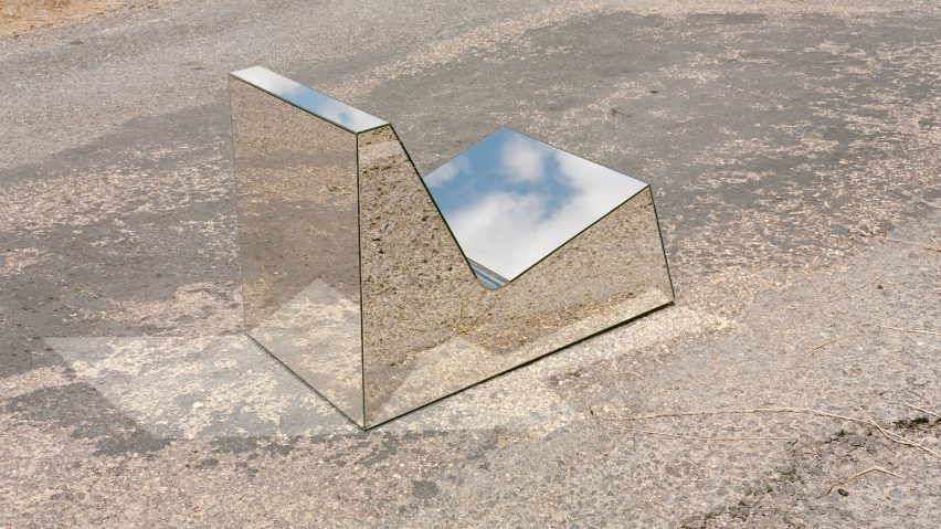 A chair with a mirrored surface on a paved ground