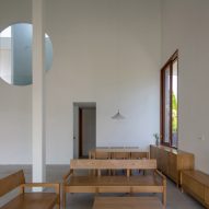Interior space with concrete flooring, wood furniture, white walls and a circular window