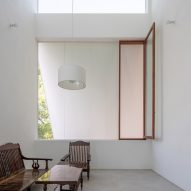 Interior space with concrete flooring, white walls, large square windows and dark wood furniture