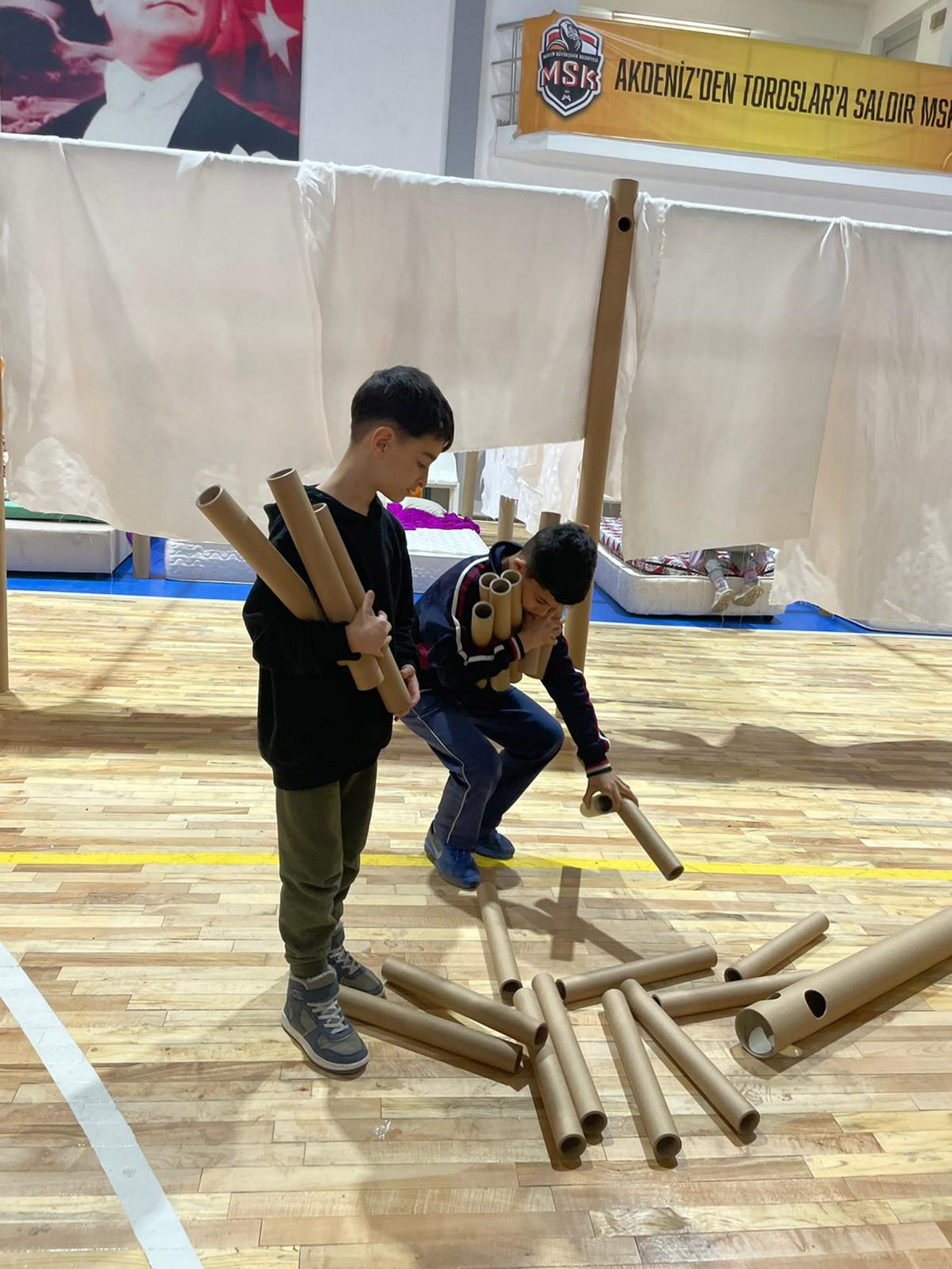 Boys with cardboard tubes used to build shelters