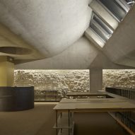 A room with a curved concrete ceiling, skylights and white brick walls