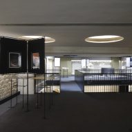 A room with dark carpets, white brick walls, circular recessed ceiling lights and freestanding displays