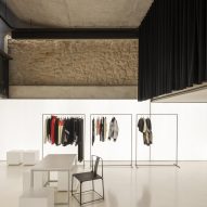 A retail showroom with white walls and floors and black curtains covering the upper parts of the walls