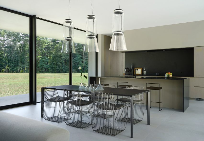 Кухня в стеклянном доме с прямолинейным столом и прозрачными стульями