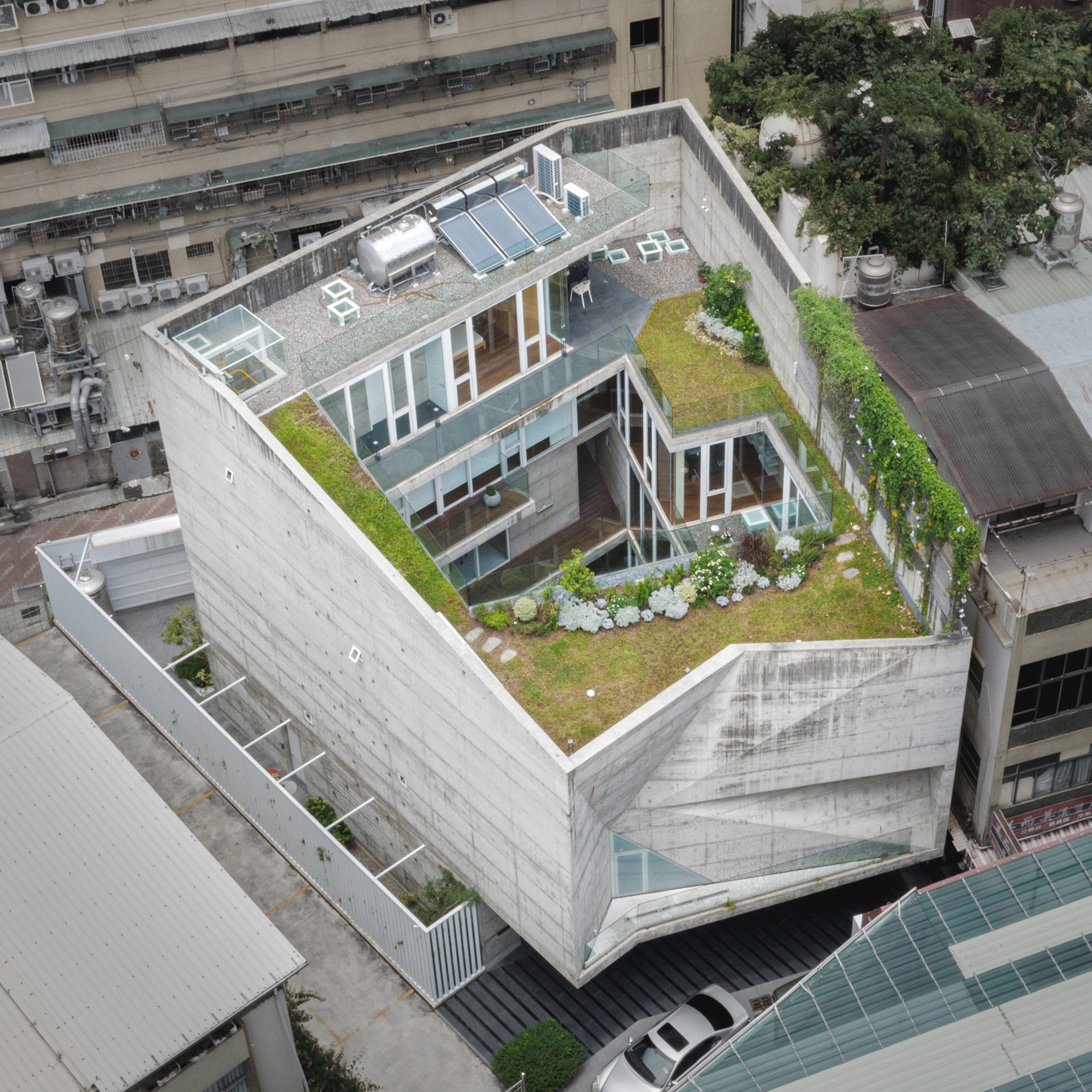 Aerial view of an angular concrete home with a central courtyard and green roof