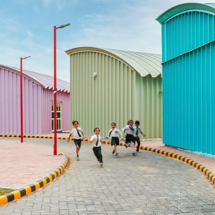 Blue, Green and pink steel structures along a curved pathway with school children playing
