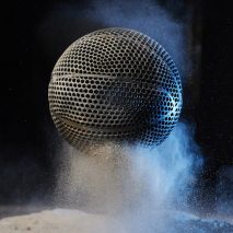 Black airless 3D-printed basketball by Wilson bouncing on a powder material