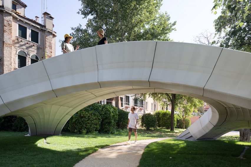 Man walking underneath the arch of the Striatus 3D-printed concrete footbridge
