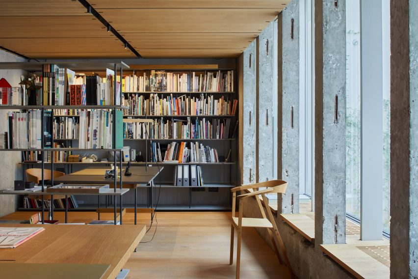 A studio with wooden floors, table and chairs, and a grey bookshelf