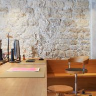 Wooden desk and swivel chairs next to a white brick wall