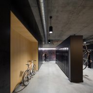 Interior of an office storage space with concrete flooring, wood wall panelling and black metal lockers