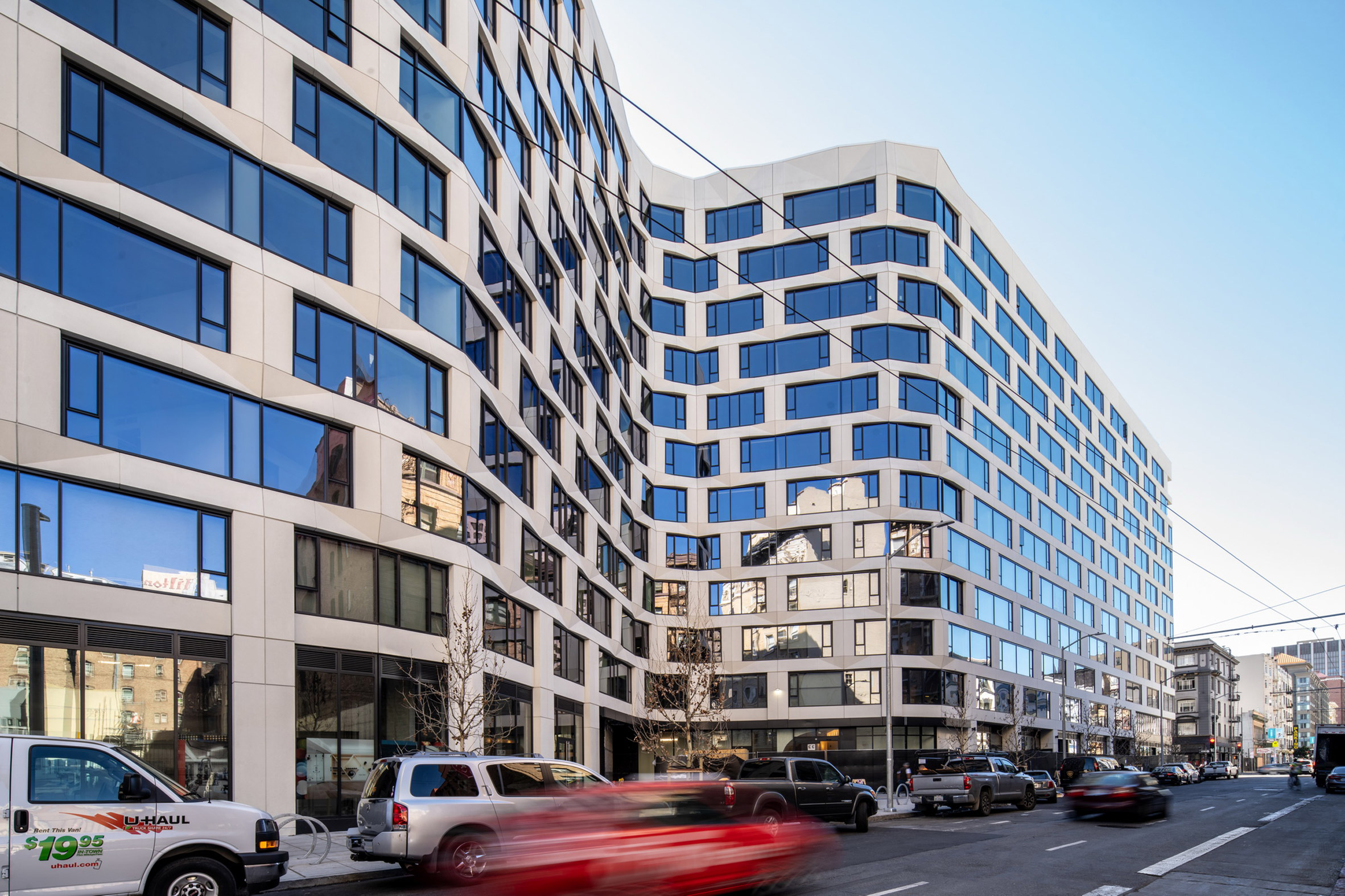 Curving mixed-use building with faceted panels on its facade by Handel Architects