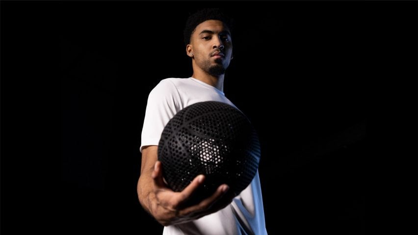 Man in a white t-shirt holding the black airless 3D-printed basketball by Wilson