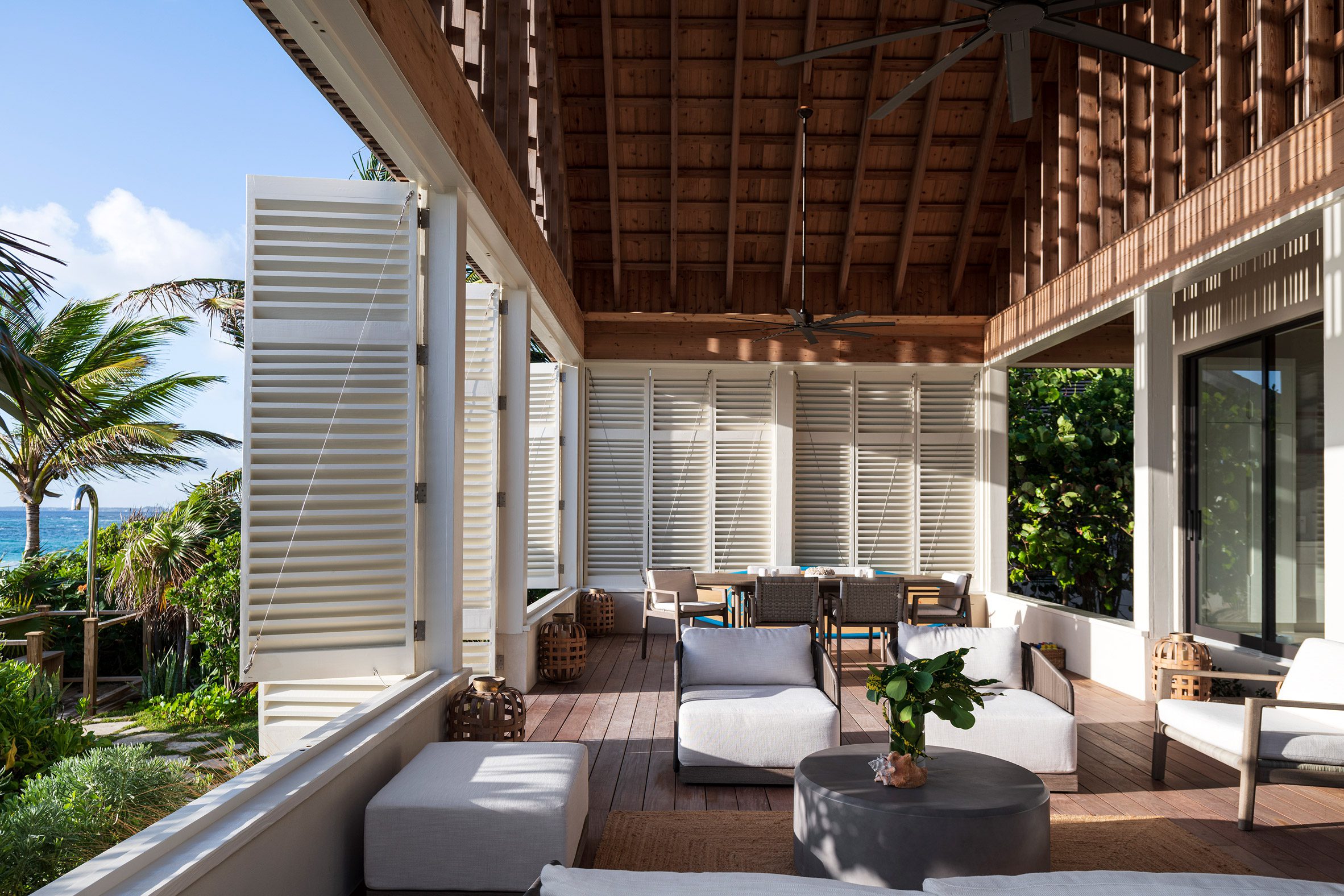 Indoor-outdoor room with white shutters at Bahamas beach house by Brillhart