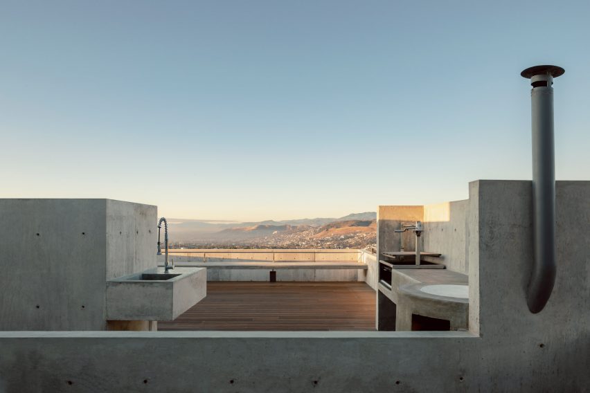 Expansive terrace with a rectilinear concrete sink and wooden decking by Espacio 18 Arquitectura