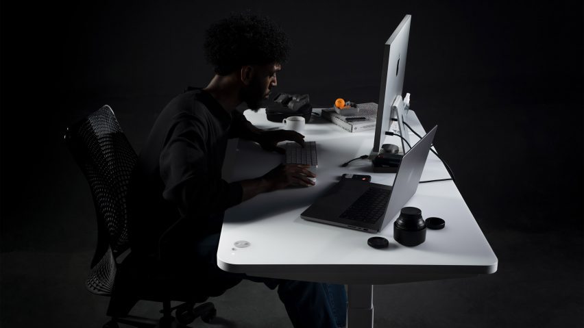 Person working seated at a desk with laptop and monitor