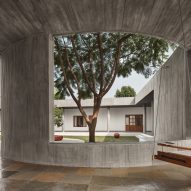 Covered concrete walkway with a swing seat and an opening in the wall that overlooks an outdoor courtyard