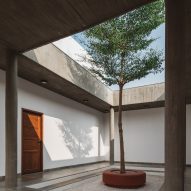 A courtyard with a surrounding concrete structure and a central tree