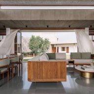 Open-plan living and dining space with concrete structure and a large opening leading to a courtyard