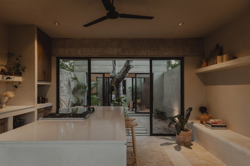Interior of a concrete kitchen with glass sliding doors leading to a courtyard with a tree