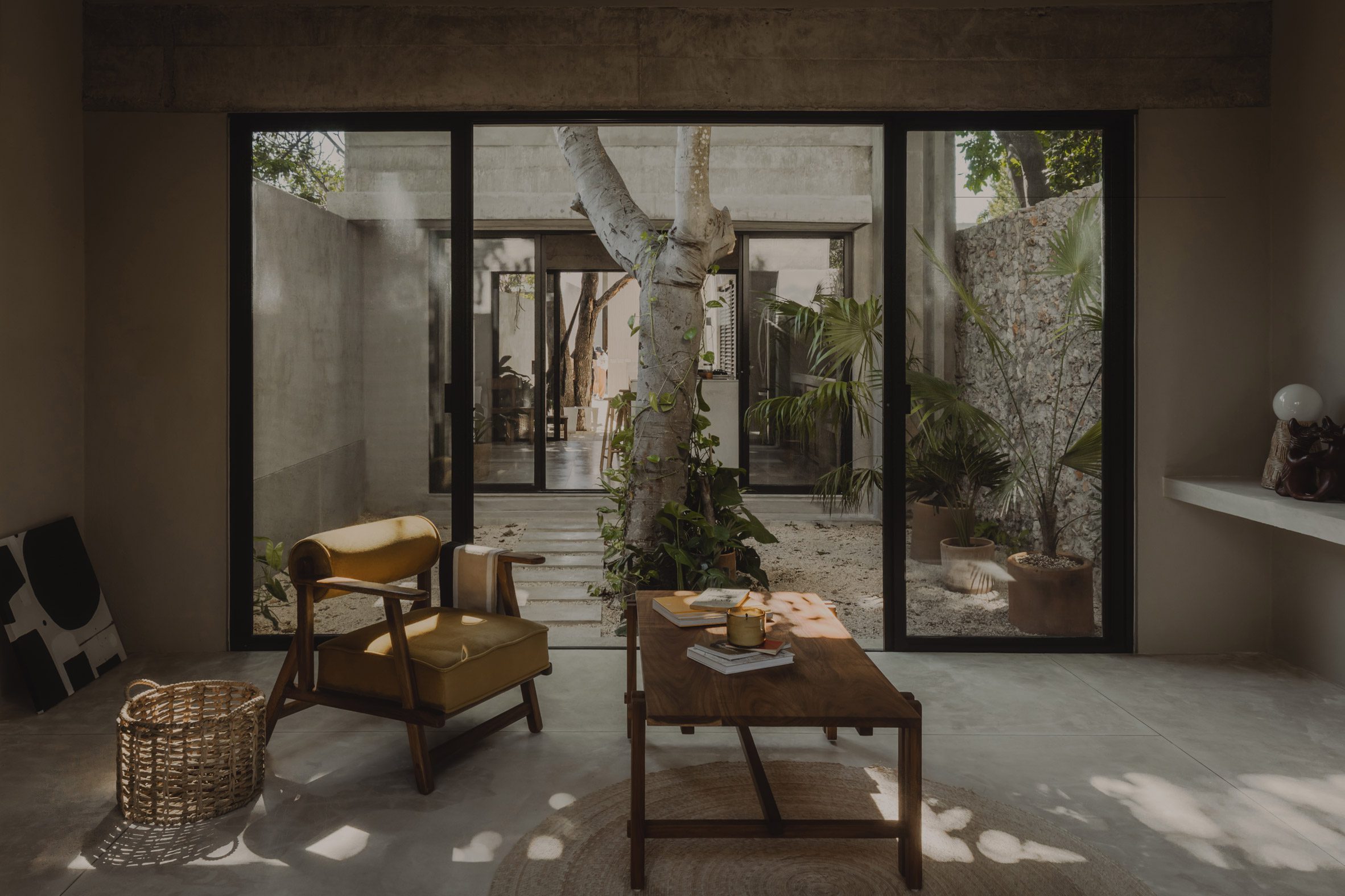 A living spaces with lounge chairs and sliding glass doors leading to a courtyard with a tree