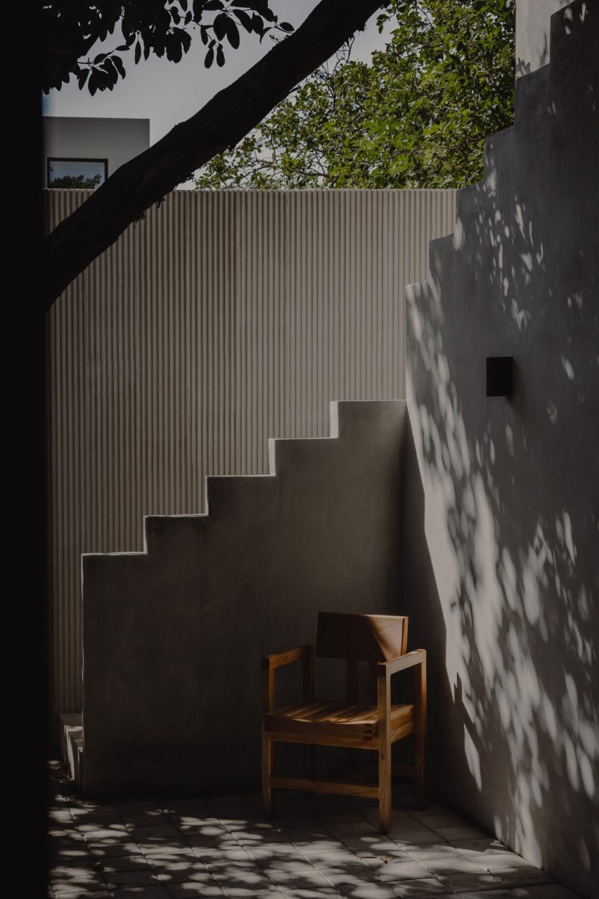 Patio space at El Tiron house by FMT Estudio with concrete walls and wooden chair