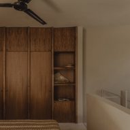 A bedroom with wood wardrobes on a mezzanine level in a concrete home by FMT Estudio