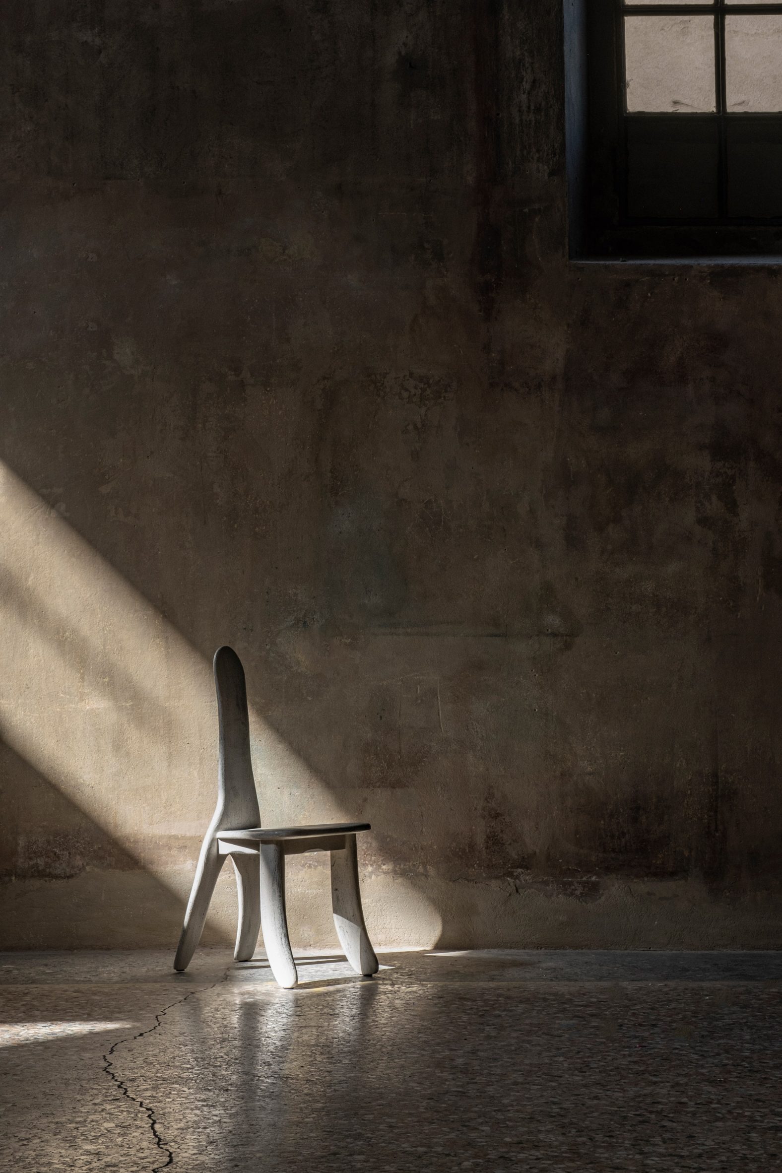 Minimalist white chair partly in shadow with beam of light