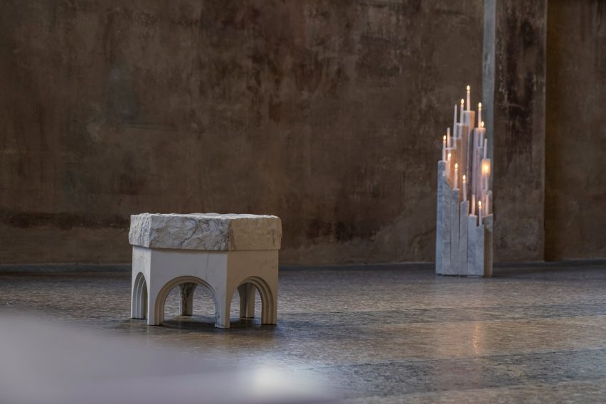 Hexagonal table with stone top and marble sculptural candelabra on terrazzo flooring