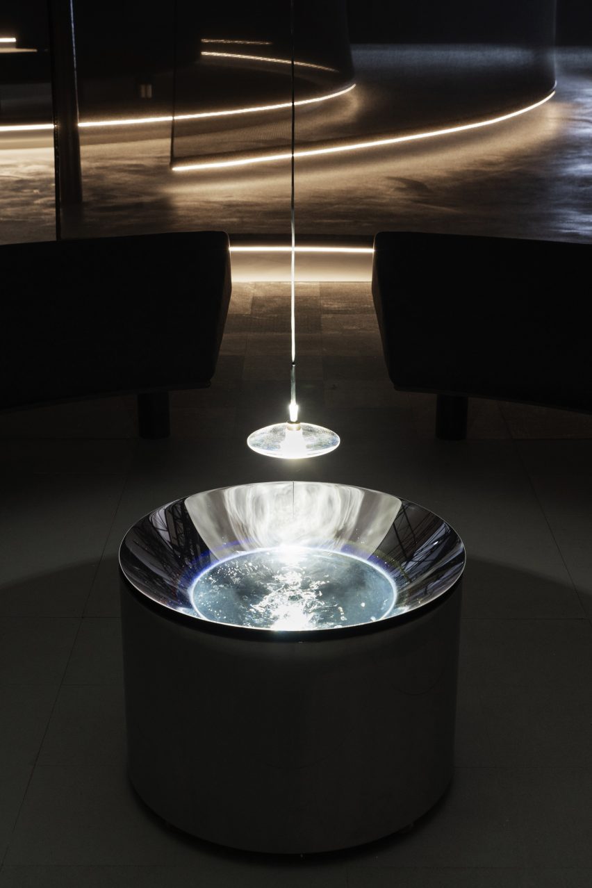 Light and lens hanging over a steel basin by Lachlan Turczan