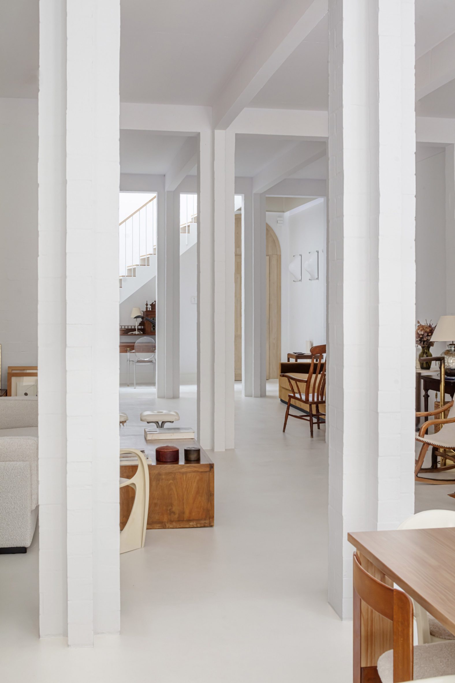 White interior space with square columns and wooden furniture