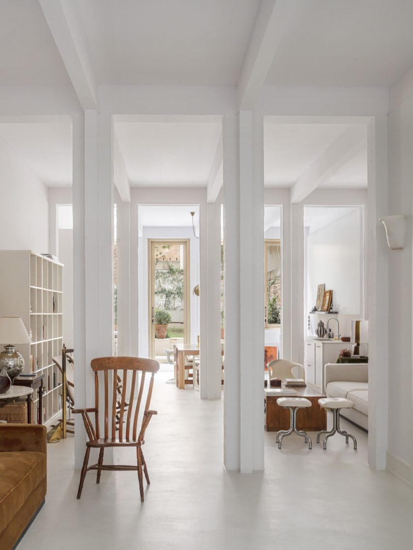Interior of a white Barcelona apartment with square columns and glass doors leading to a patio