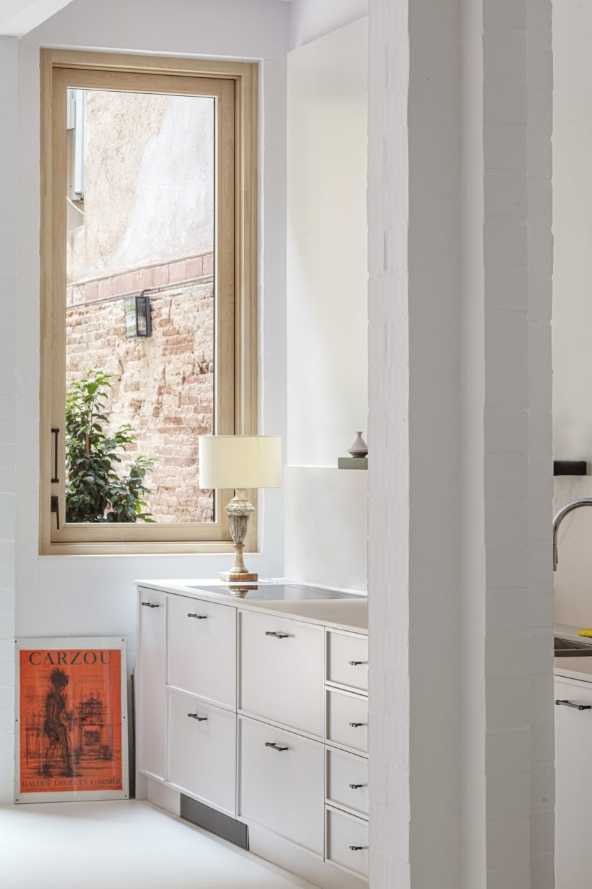 آشپزخانه خانه 1616 با کابینت های سفید، کف سفید، دیوارهای سفید و پنجره ای با قاب چوبی