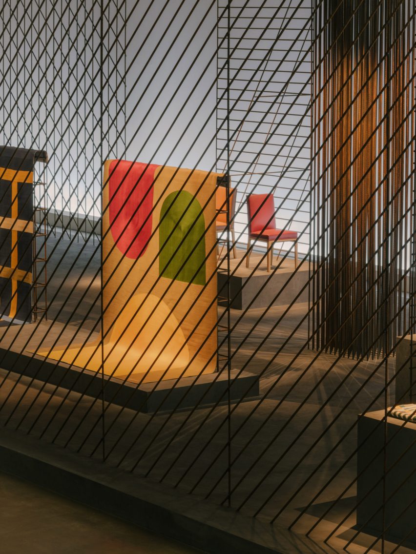 Iron cage featuring colourful textiles within it by Hermès