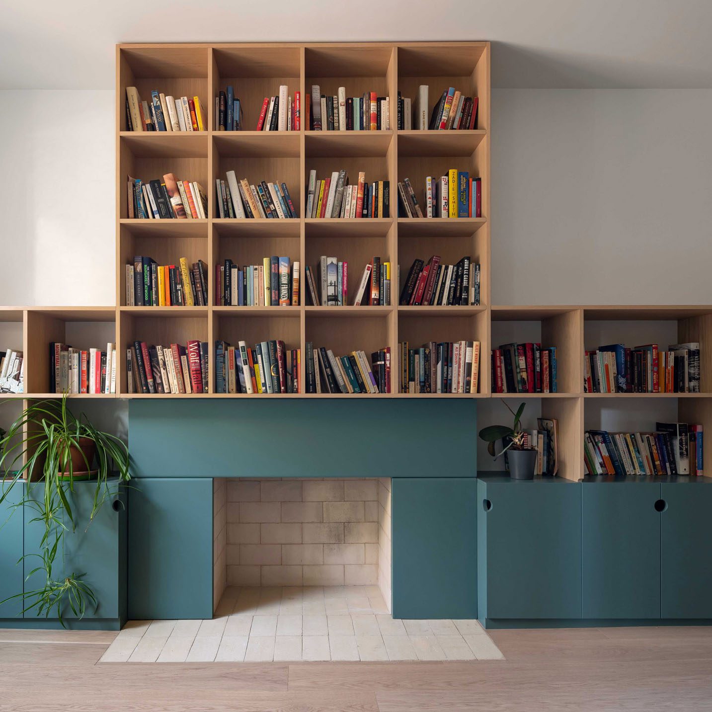 Teal fireplace with oak bookshelves above